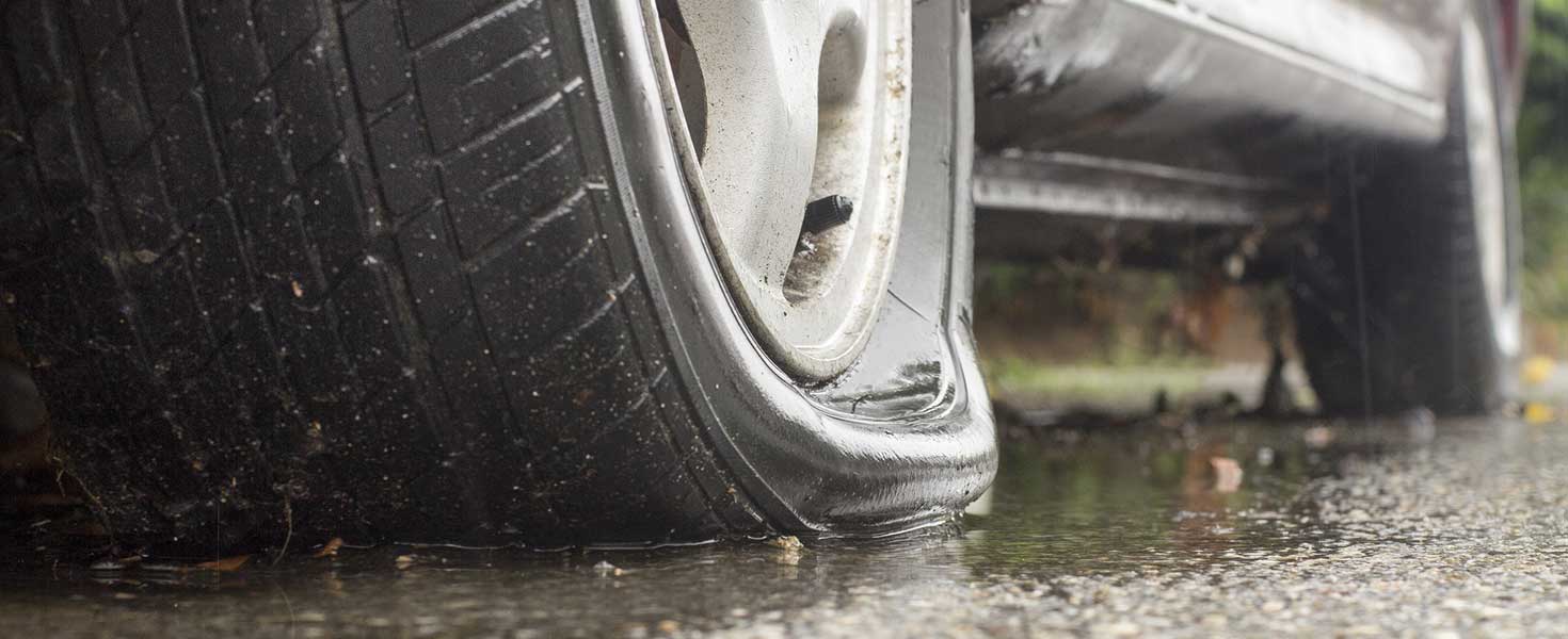 Car flat tire in rainy day