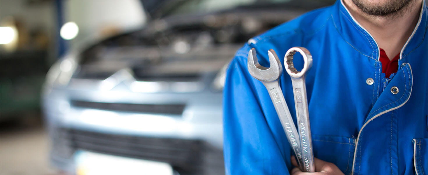Auto mechanic holds wrench in hand at auto repair shop